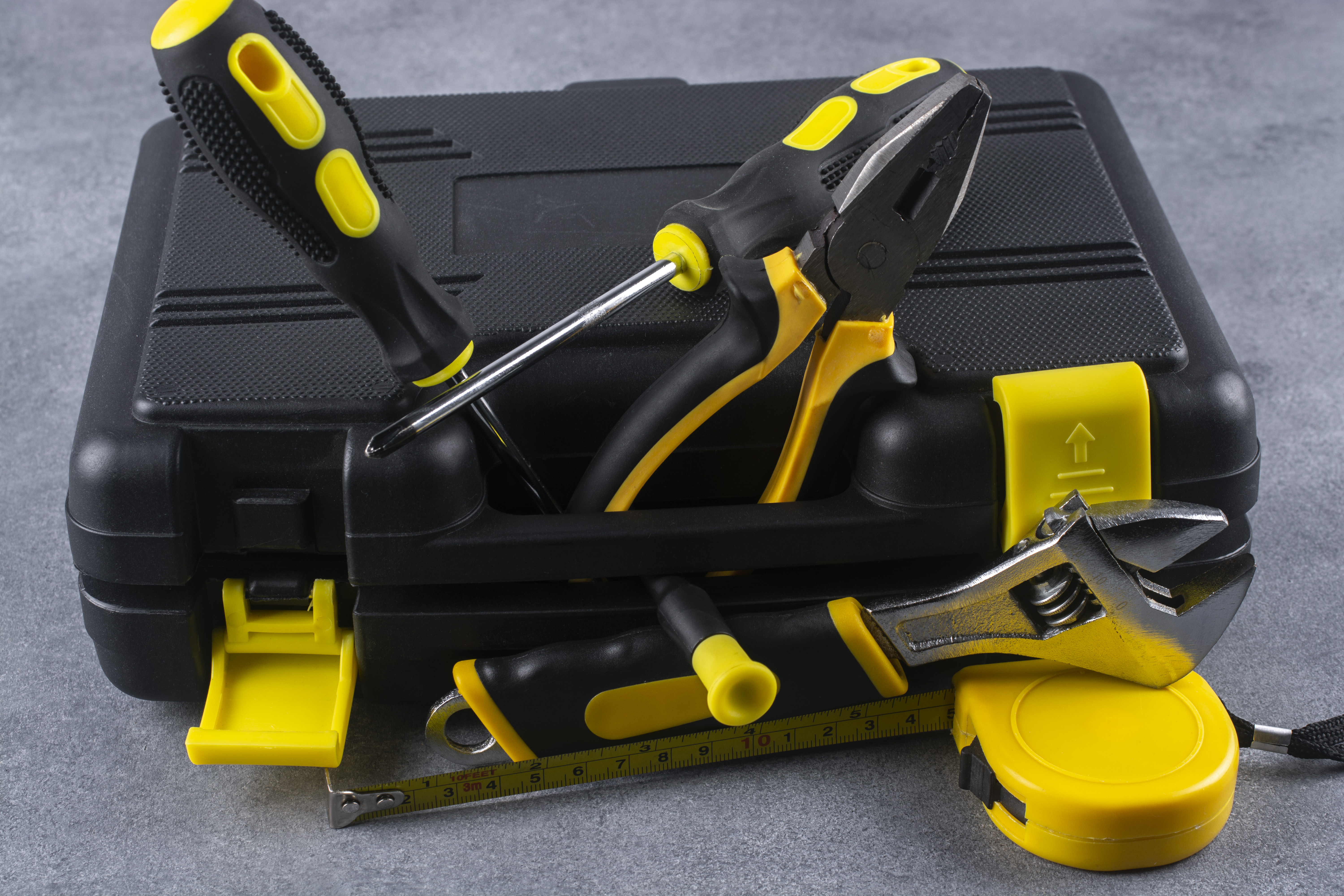 A close-up photograph of a black plastic case filled with various repair tools, such as screwdrivers, pliers, and wrenches, arranged neatly and organized for easy access