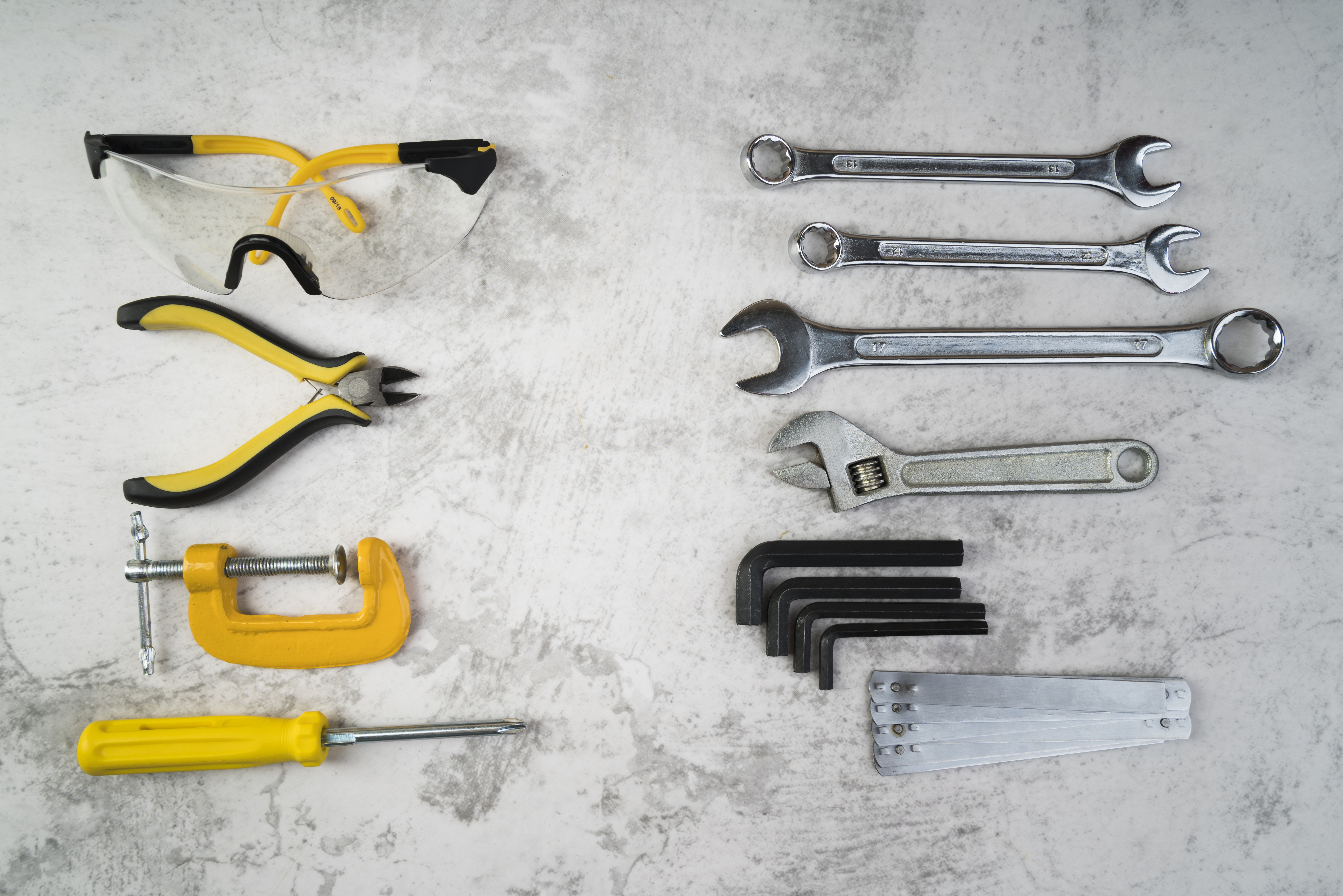 A top-view photograph of a collection of different types of tools, such as hammers, screwdrivers, pliers, wrenches, and more, arranged in a scattered or organized manner, showcasing a variety of shapes, sizes, and functions