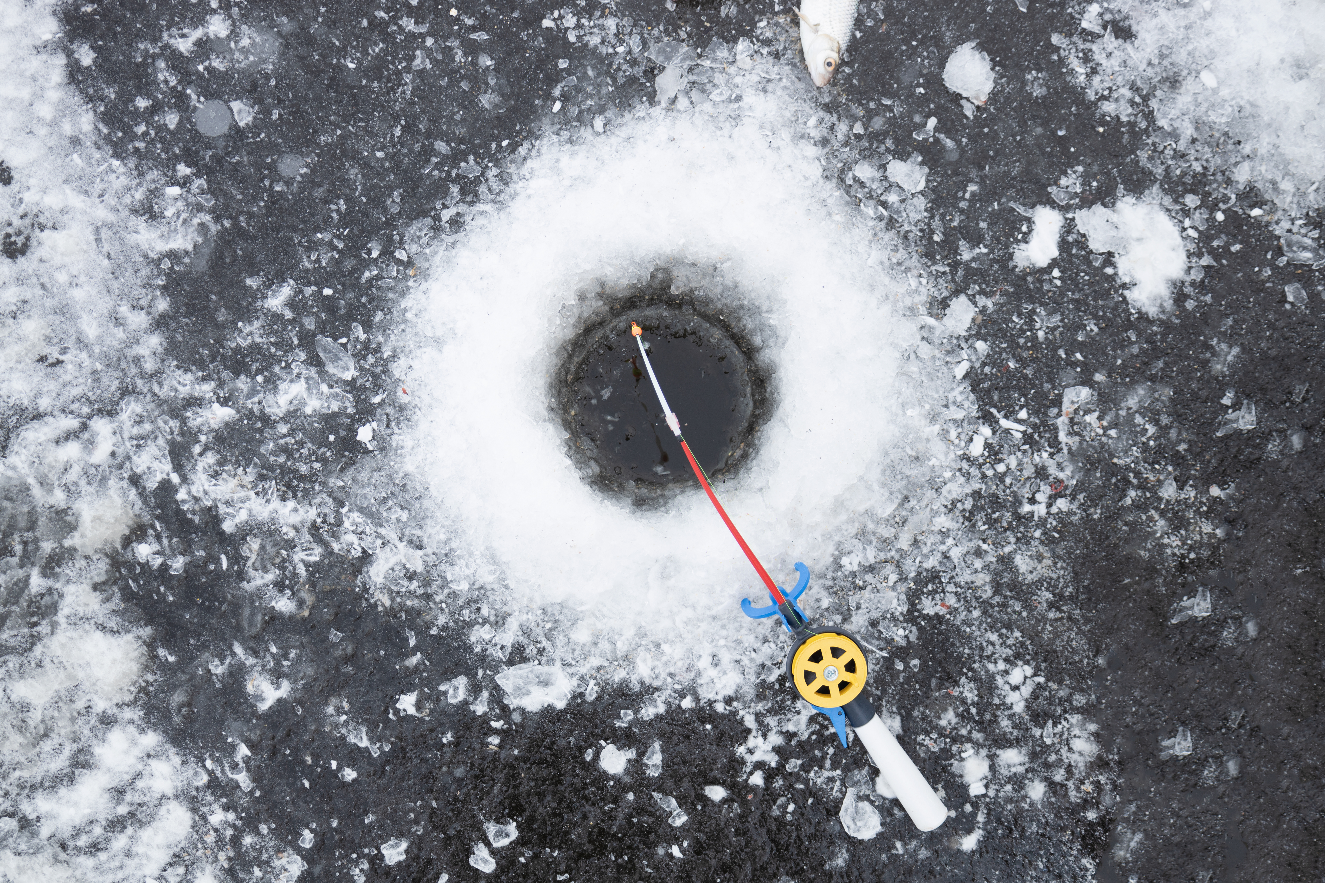 Winter fishing rod for ice fishing near hole lies on snow